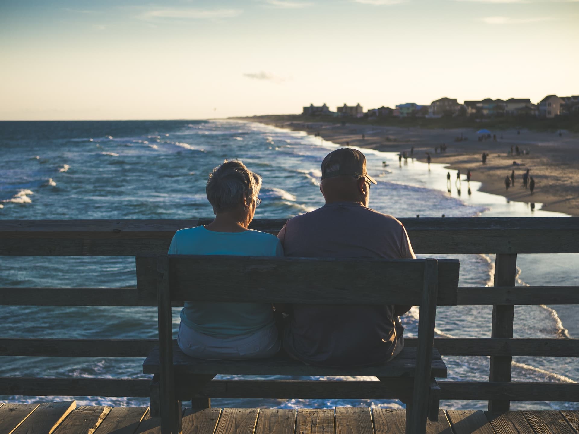 A man and woman sitting on a bench overlooking the beautiful Emerald Isle beach, North Carolina, USA - Photo by James Hose Jr on Unsplash