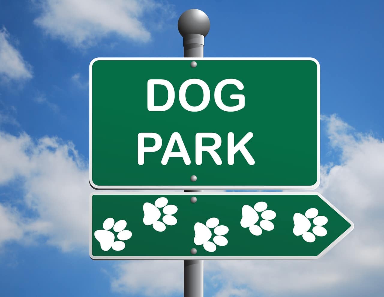 A green dog park sign with white writing on it