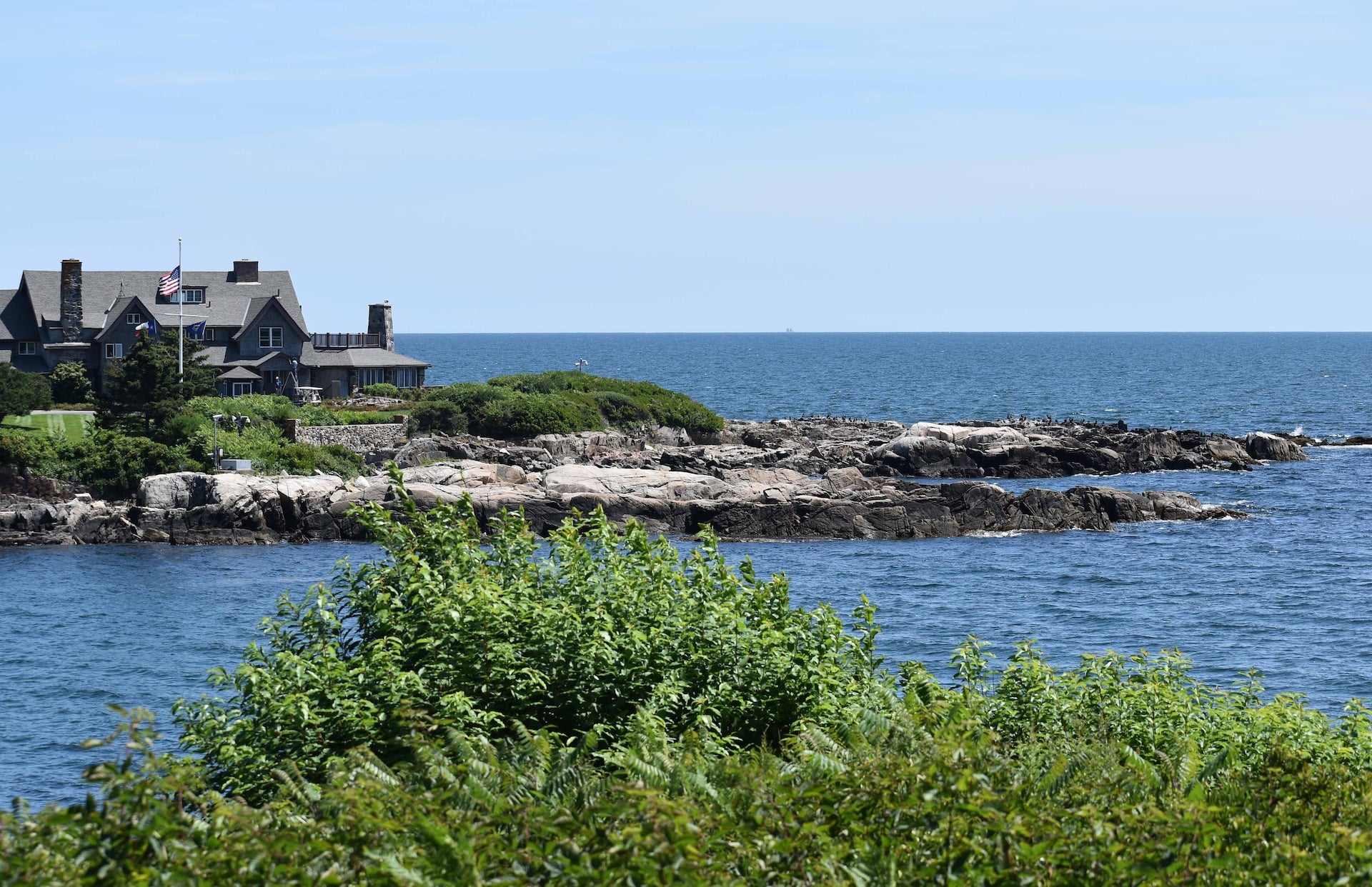Looking out at the Atlantic Ocean at one side of the Bush Estate, with a sailboat far off, and birds on the rocks - Kennebunkport, Maine
